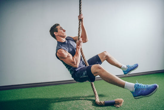 Man doing rope climbs in the gym